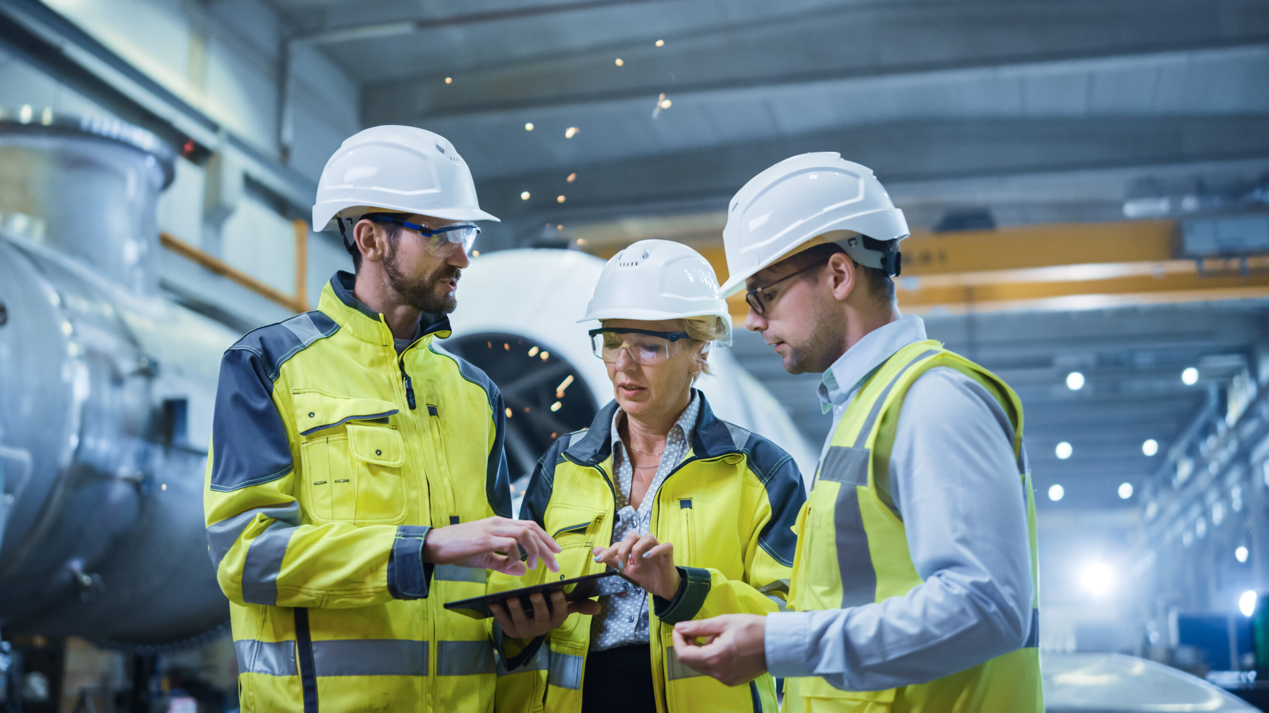 Three heavy industry engineers in hard hats and safety gear at a pipe manufacturing factory, illustrating FDI factory setup legal services in Nghe An Province